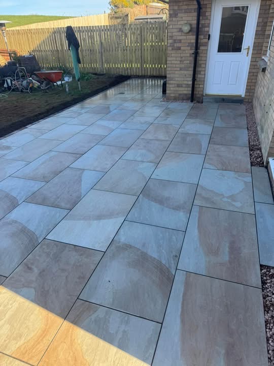 Buff sandstone patio with tegula brick course leading to the back door