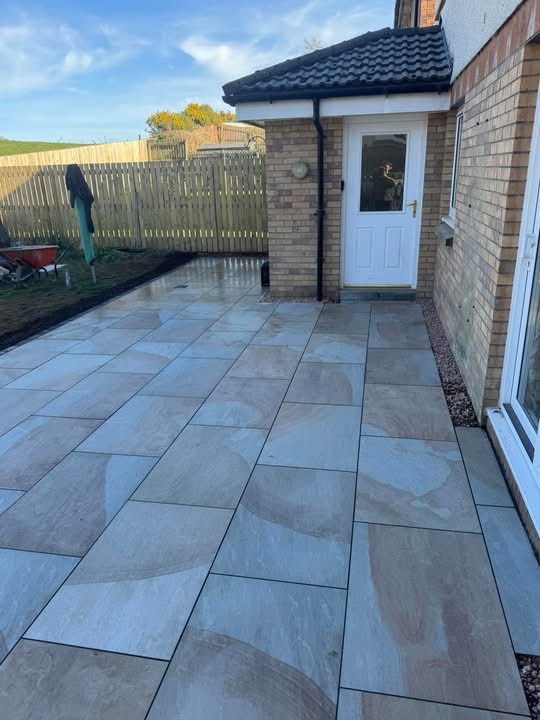 Buff sandstone patio at the back door of the new-build with tegula edging detail