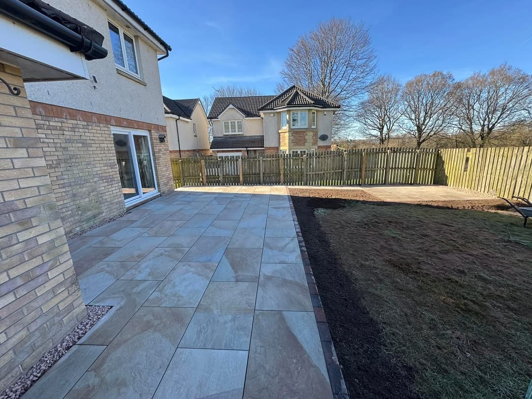 Buff sandstone patio meeting the lawn area at the new-build, tegula border running the length