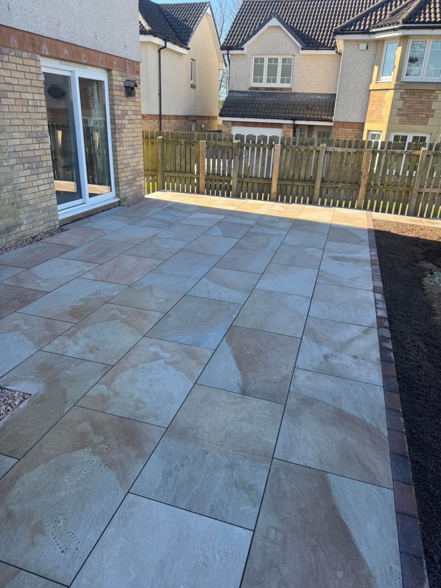 Wide view of the buff sandstone patio at the rear of the new-build property