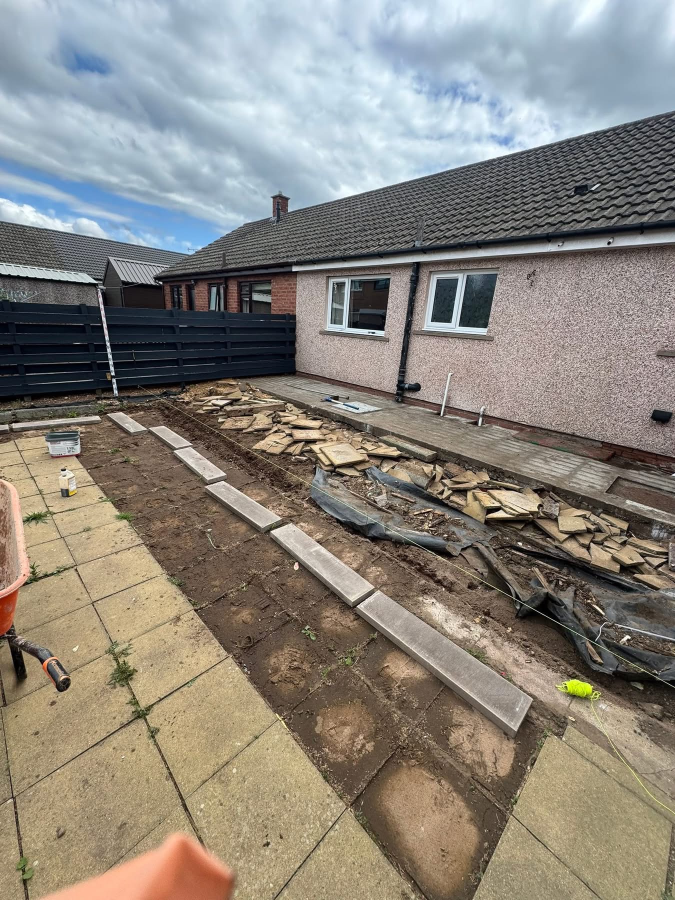 Before — broken concrete slabs and old paving being lifted at the rear of the bungalow