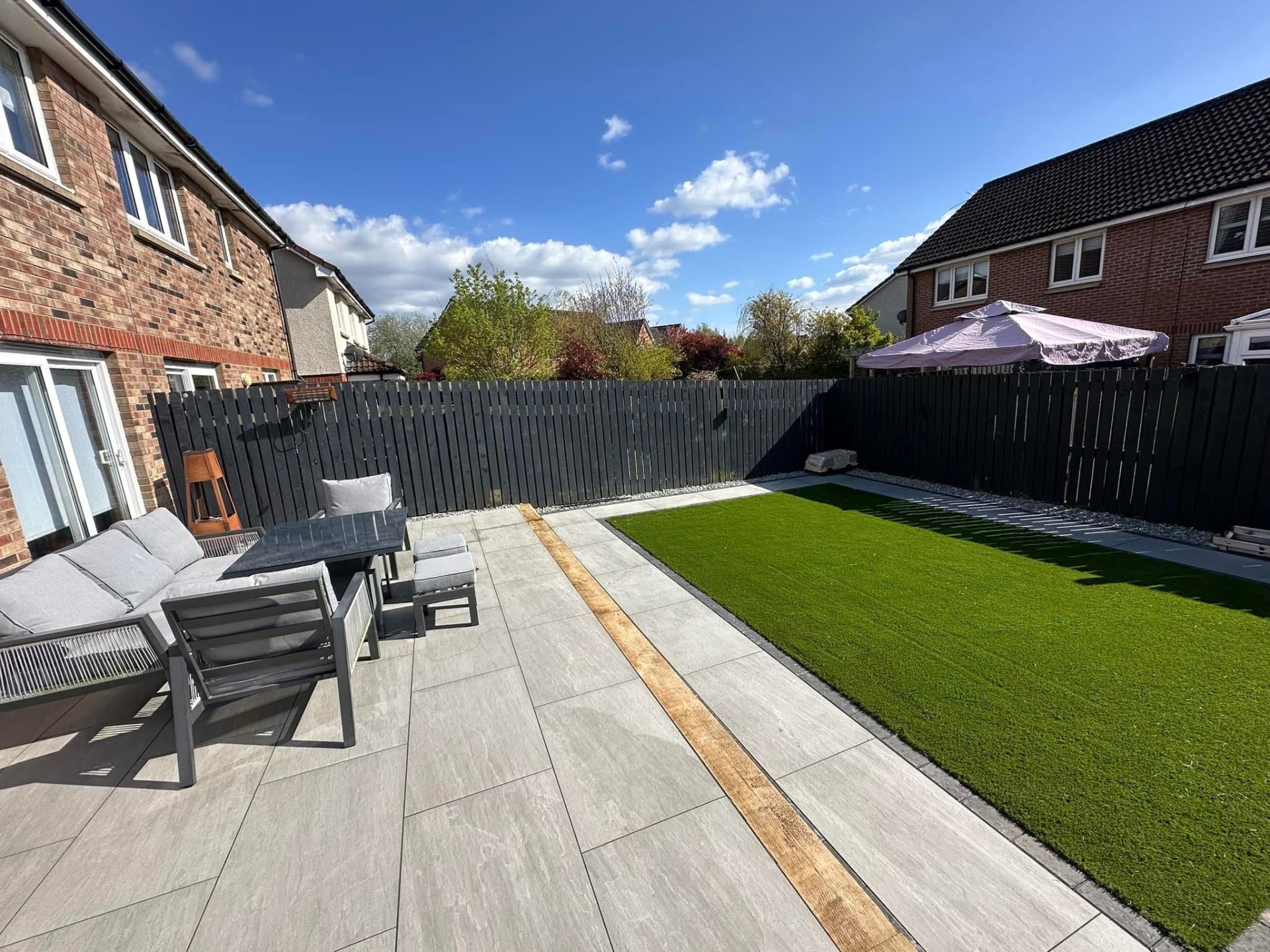 Artificial lawn set into a porcelain patio with timber inlay — Carlisle