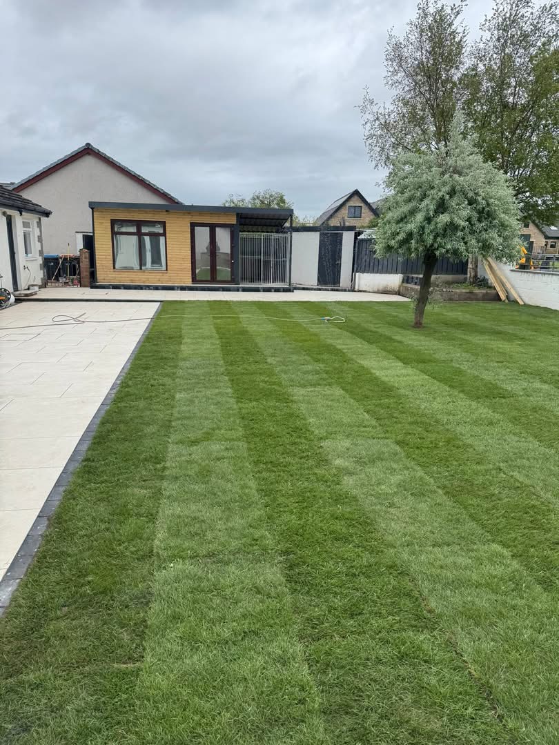 Freshly-laid striped lawn beside porcelain patio leading to a timber-clad garden room — Bell residence, Dornoch