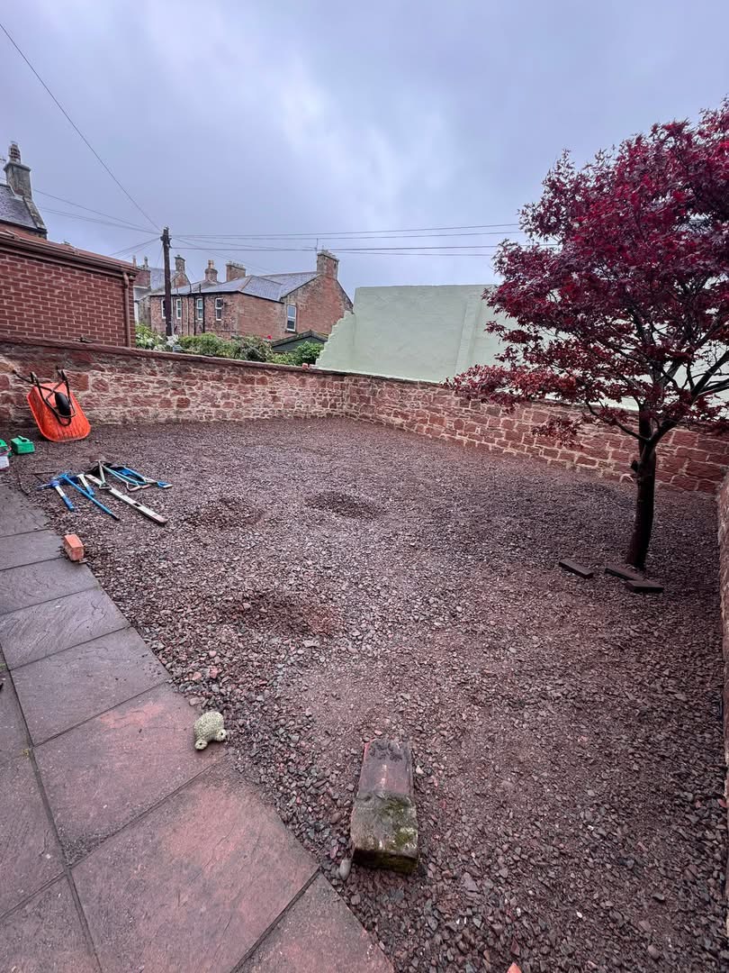 Before — walled garden stripped back to compacted sub-base with tools on site, ready for the new sandstone patio