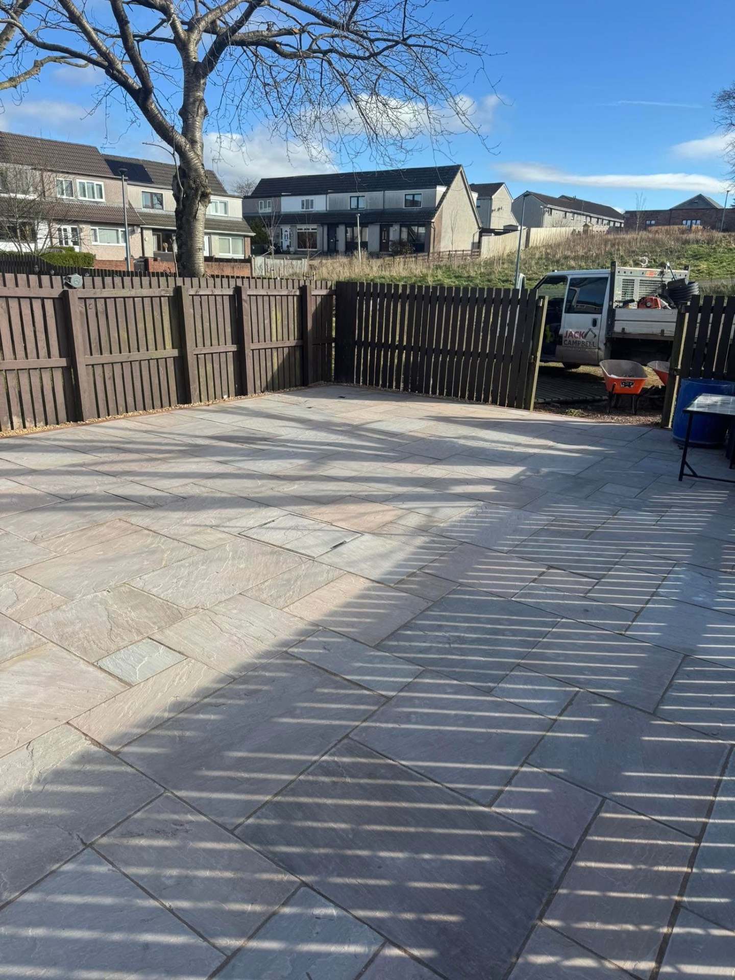 Wide view of the random-coursed Indian sandstone patio with garden fencing